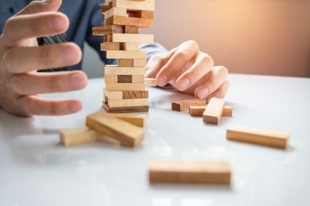 planificacion-riesgo-estrategia-negocios-juego-empresarios-colocando-bloque-madera-torre_1423-19